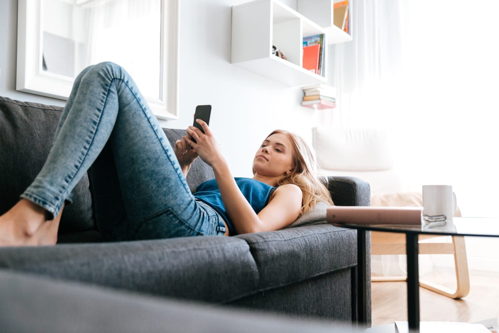 Une voyageuse détendue sur le canapé consulte son téléphone